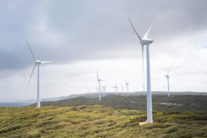 Majestic wind turbines harnessing energy in a vast green landscape under cloudy skies.