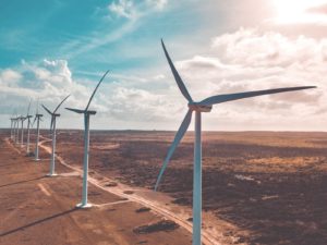 wind turbines on brown sand under white clouds and blue sky during daytime